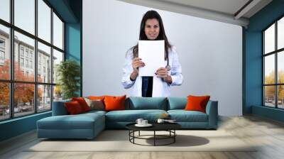 Portrait of middle age woman model holding white empty paper. Nurse, doctor, scientist, therapist, pharmacist, isolated on gray background studio shot, in white coat uniform. Place for your text in co Wall mural