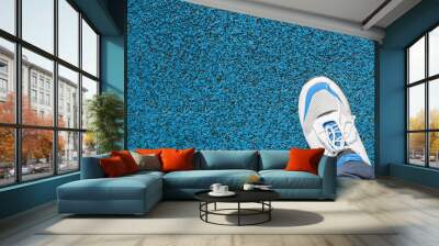 Man in sports sneakers for running, standing on a rubberized, blue covering outside. Close-up, top view. Active lifestyle, workout concept Wall mural