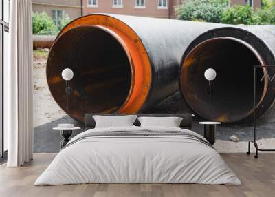 Plumbing repair outdoors concept. Two new industrial pipes lying on ground, close-up Wall mural