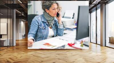 woman speaking at the phone in the office in front of the computer Wall mural