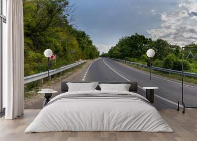 Road landscape forest and mountain. Empty long mountain road to the horizon on a sunny summer day with dramatic cloudy sky. Highway turn panoramic view. Wall mural