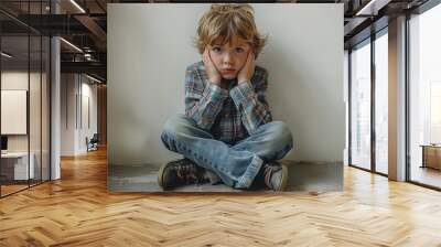 an autistic child cries and covers his ears, sits near the white wall Wall mural