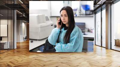 attractive female lab worker using mobile phone at her workplace in the laboratory. scientist discus Wall mural