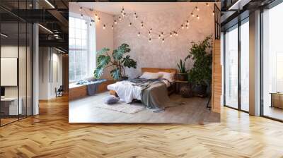 Cozy bedroom area at luxury studio apartment with a free layout in a loft style with big panoramic window and green plant. Wall mural