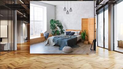 Cozy bedroom area at luxury studio apartment with a free layout in a loft style with big panoramic window and green plant. Wall mural