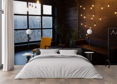 Modern interior in a dark color with a leather sofa and large window. Loft style living room Wall mural