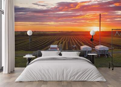 Sunset over farm with striped fields, modern equipment and electricity Wall mural