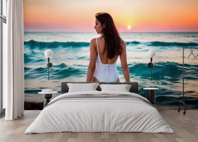 A curvaceous girl with dark long hair in a white one-piece swimsuit stands with her back in the sea water against the background of the horizon of the blue sky and the sea at sunset. Generative AI. Wall mural