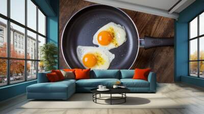 frying eggs in pan on wooden table Wall mural