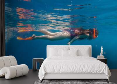 Girl in orange swimming mask and flippers dive in deep sea Wall mural