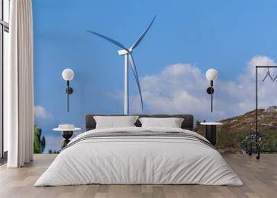 white wind turbine on a green hill against a blue sky Wall mural