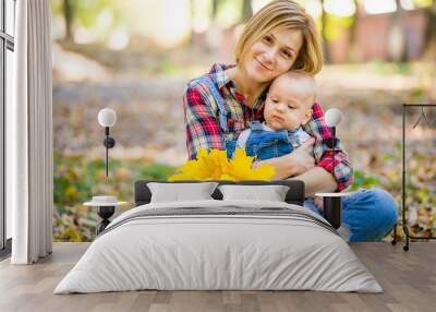 young mother playing with baby in the park in autumn Wall mural