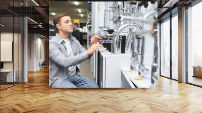 A buyer shopping for bathroom equipment in hardware store. Touching faucet crane or water tap Wall mural