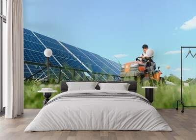 A man drives a lawnmower near solar panels. Concept of solar energy Wall mural