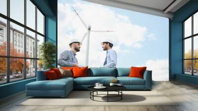 A team of male engineers working together at wind turbine generator farm. Wall mural