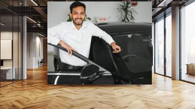 A young Indian man chooses a new car at a car dealership Wall mural