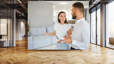 A young salesman consults a female customer in a furniture store Wall mural