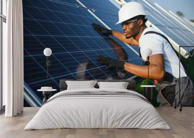 African American engineer maintaining solar cell panels. Technician working outdoor on ecological solar farm construction. Renewable clean energy technology concept Wall mural