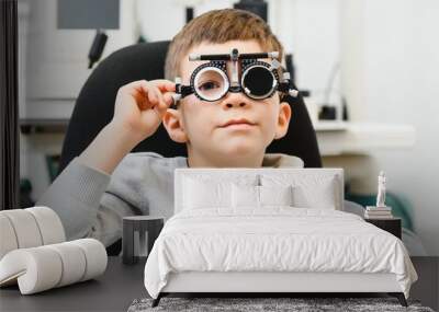 Cheerful child boy in glasses checks eye vision pediatric ophthalmologist. Wall mural