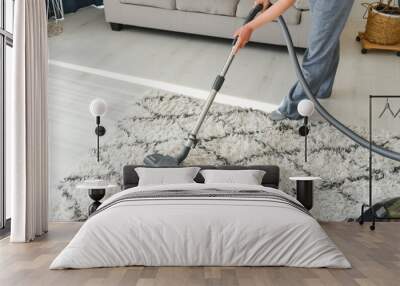 Cleaning concept. woman cleaning carpet with vacuum cleaner. Wall mural