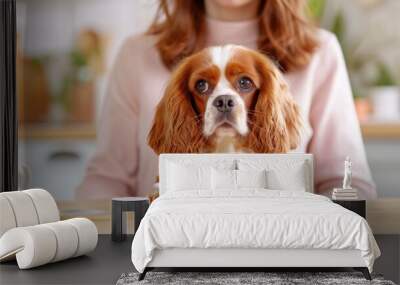 Cute cavalier king charles spaniel sits at table with white bowl in cozy kitchen. pet companionship and adorable domestic scenes. Wall mural