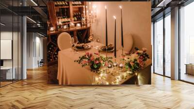 Dinner setting, date for two, Valentine's Day evening, burning candles. Candlelight date in a wine cellar. Glasses for wine, bouquet of flowers and decor on table. Romantic dinner at home at night. Wall mural