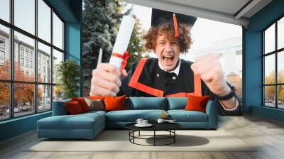 Excited male student in mantle scream graduate from university finish course studying. Happy man triumph holding college diploma in hands overjoyed with high school graduation. Wall mural