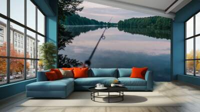 Fisherman with fishing rod, spinning reel on the background river bank. Sunrise. Fog against the backdrop of lake. Misty morning. wild nature. The concept of rural getaway. Article about fishing day. Wall mural