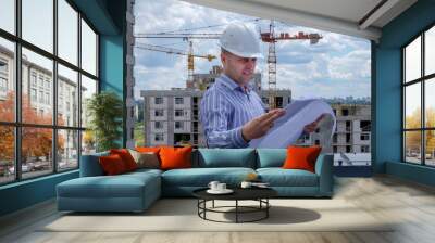 Foreman in white helmet on roof are looking at the project on the construction site. Summer, cloudy sky. Wall mural