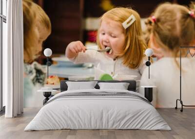 Girl 3 years sits at the table and Independently eating. Kids eat in kindergarten. Lunch. Wall mural