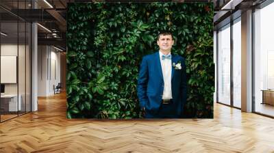 Groom stands near greenery in the Botanical green garden. Wedding ceremony on nature. Wall mural