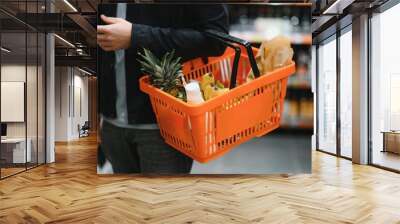 Handsome man buying some healthy food and drink in modern supermarket or grocery store. Lifestyle and consumerism concept. Wall mural