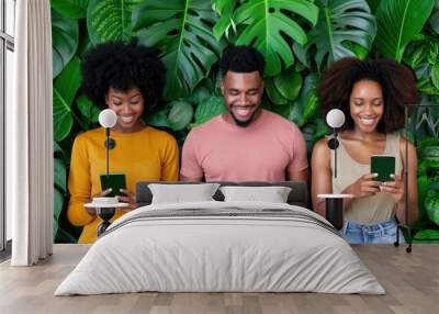 Happy diverse friends using smartphones against a tropical leafy green background Wall mural