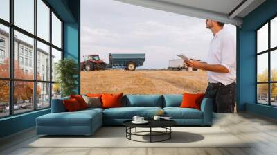 Happy farmer standing in a wheat field after the harvest. Agriculture concept Wall mural