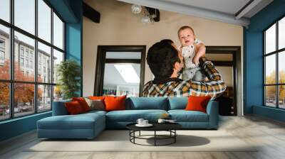 Happy father with his son playing at home on the bed. Portrait of dad with baby boy. Wall mural