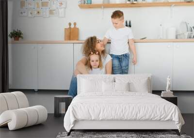 Happy young family, mom with little children sit on warm wooden floor in new modern design kitchen, mother with excited small kids relax rest in own renovated apartment, moving concept Wall mural