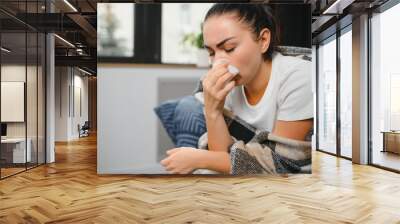 healthcare, cold, allergy and people concept - sick woman blowing her runny nose in paper tissue at home. Wall mural