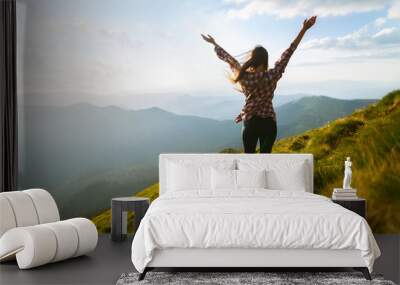 Hiker woman standing with hands up achieving the top. Girl welcomes a sun. Conceptual design. Successful woman hiker open arms on sunrise mountain top. Happy young blonde woman portrait Wall mural