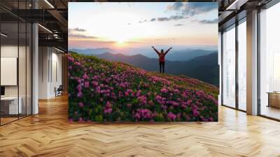 Hiker woman standing with hands up achieving the top. Girl welcomes a sun. Successful woman hiker open arms on sunrise mountain top. Magic pink rhododendron flowers on summer mountains Wall mural