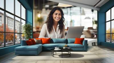 Indian business woman working on a laptop in a bright, open workspace. A young Indian student or remote teacher is working in online education, flexibility of remote work. Generative AI Wall mural