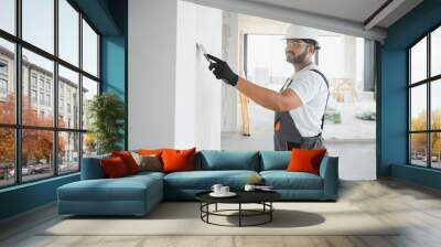 Indian Male builder in work overalls plastering a wall using a construction trowel. Wall mural