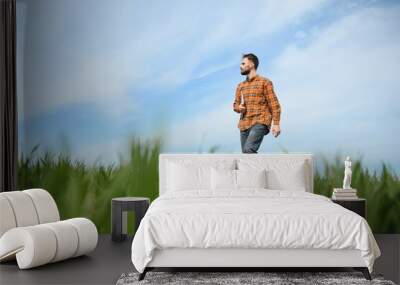 male agronomist on a green agricultural field of wheat Wall mural