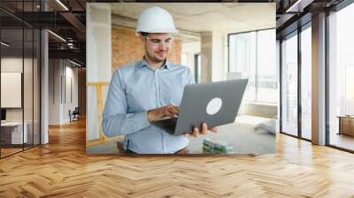 Male architect working on laptop at construction site Wall mural