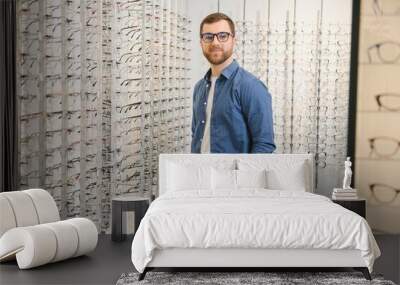 male client chooing new eyeglasses frame for his new eyeglasses in optical store Wall mural