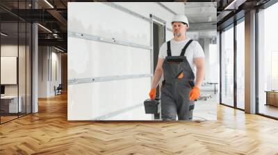 Man Builder. Architect is standing in building. Portrait of thinking builder. Builder architect in unfinished building. Architect in working uniform. Wall mural