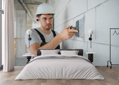 man drywall worker using trowel for plasterer putting stucco on plasterboard white wall Wall mural