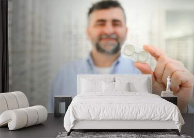 man holding contact eye lenses and container in hand, applying eye contacts from lens box Wall mural