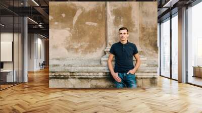 Man wearing blank t-shirt, jeans posing against street old brick wall, minimalist urban clothing style, mockup for tshirt print store. Street fashion concept. Wall mural