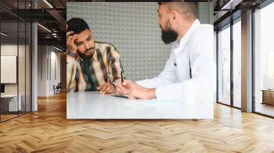 medicine, healthcare and people concept - happy doctor with clipboard and young male patient meeting at hospital Wall mural