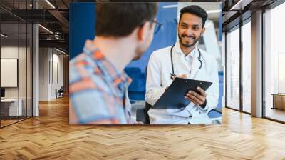 medicine, healthcare and people concept - indian doctor young male patient meeting at hospital Wall mural